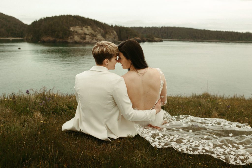 An LGBTQ+ couple sitting on a cliffside on their wedding day.