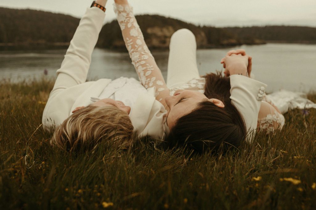 A couple laying in the grass together at Deception Pass, which is one of the best places to elope in Washington state.