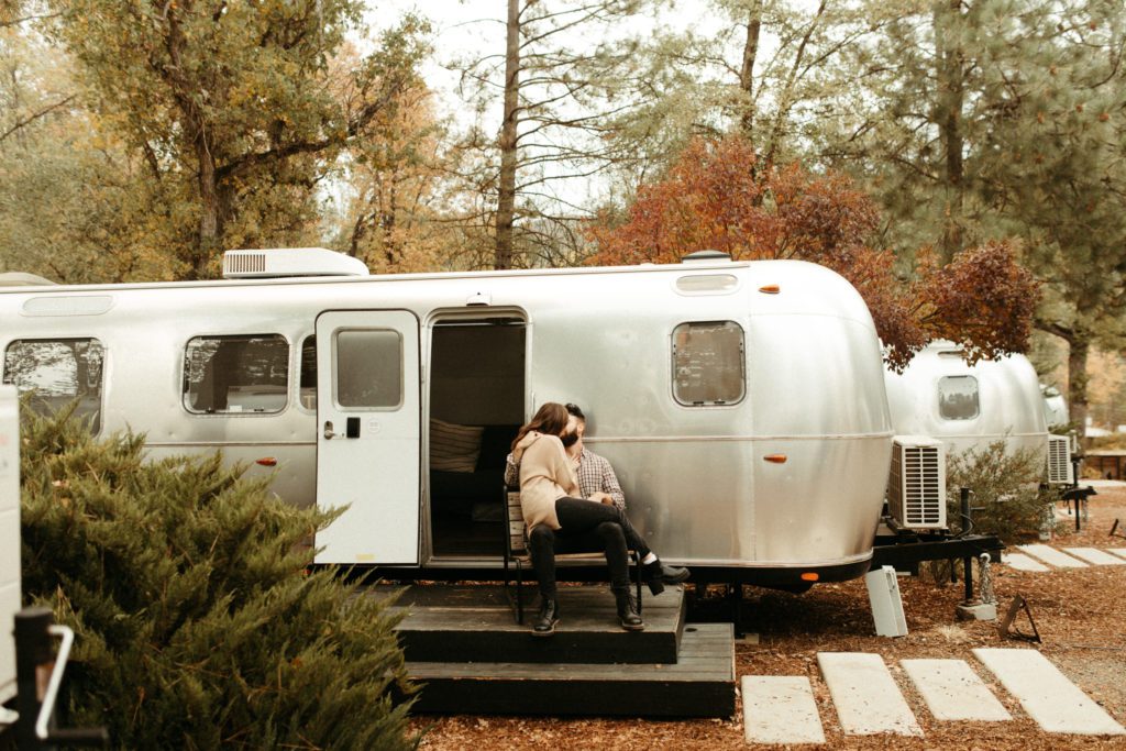 A couple sitting on the porch outside their Airstream at Autocamp Yosemite.