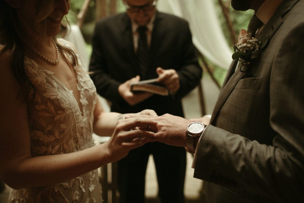 A couple exchanging rings during their ceremony at the Treehouse Point wedding venue.
