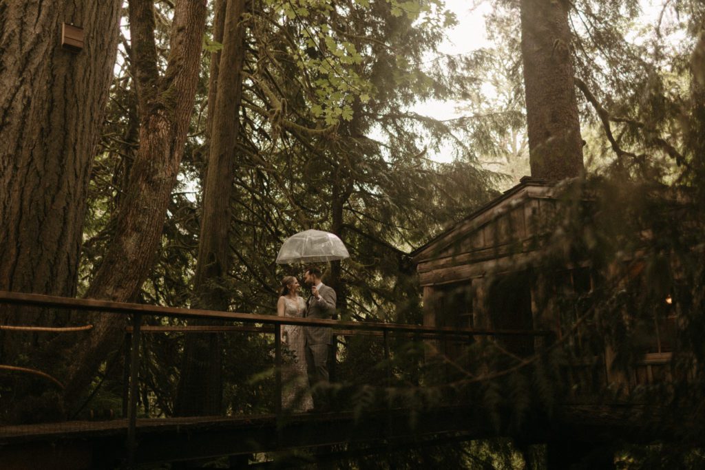 A couple standing on a bridge at the Treehouse Point wedding venue.