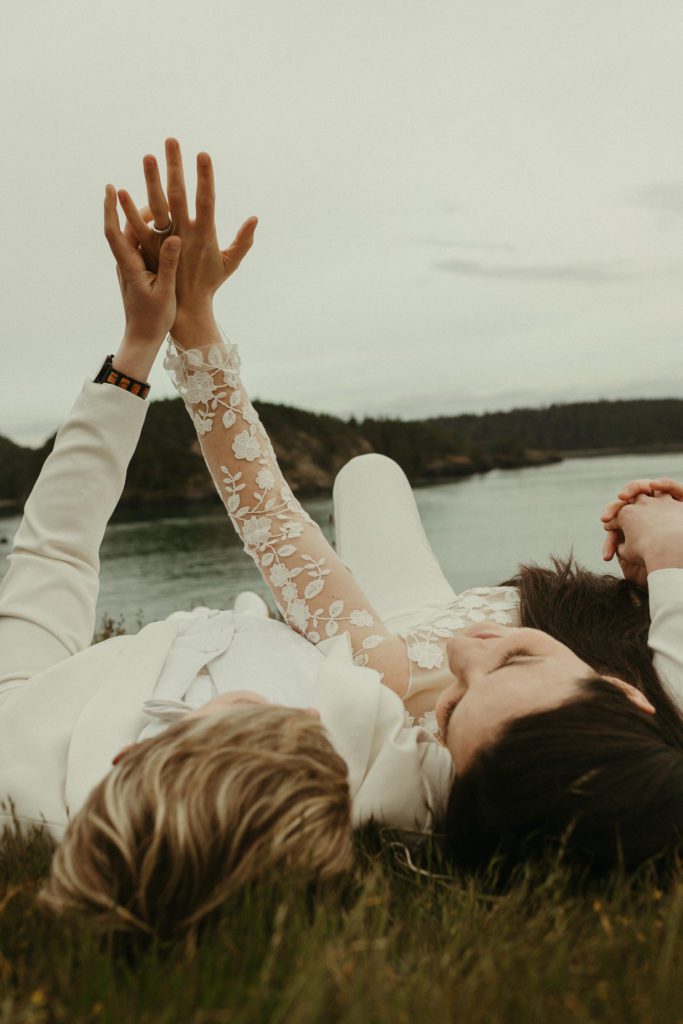 A couple laying side by side in the grass after their vow renewal at Deception Pass.