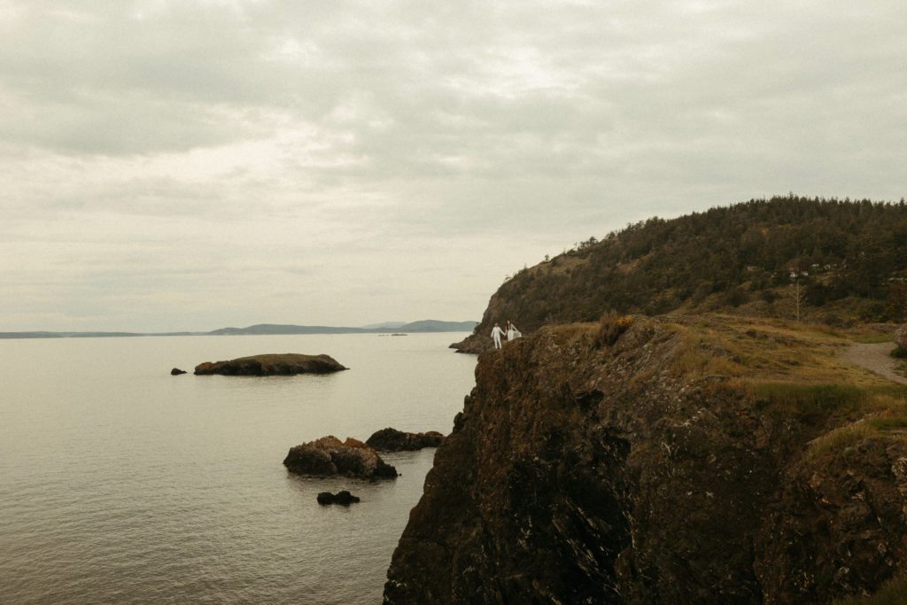 A couple standing on a cliff during their vow renewal at Deception Pass.
